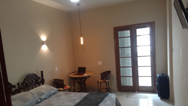 Un dormitorio con cama, escritorio y silla. Hay una ventana con persianas y una puerta.