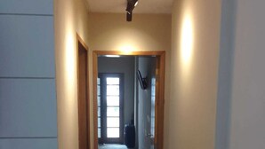 Un estrecho pasillo con piso de baldosas que conduce a una habitación con una puerta al final.