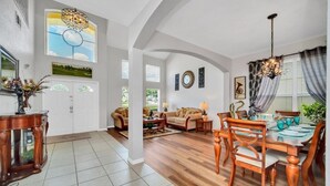 A spacious living room with a dining area, wooden flooring, and a large window with a view.