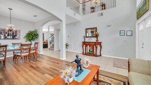A spacious living area with a wooden dining table, chairs, and a chandelier.