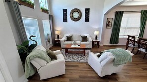 A living room with a sofa, two armchairs, a coffee table, and a decorative wall clock.