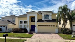 A two-story house with a garage, a front entrance, and a mailbox. - Highlands Reserve 6 Bed Pool Home - Spacious, Modern & Clean (Davenport)