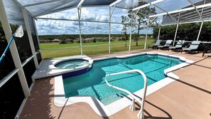 A swimming pool with a hot tub, surrounded by a covered area with lounge chairs.