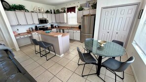 A compact kitchen with white cabinets, a central island, a refrigerator, and a dining table with four chairs.