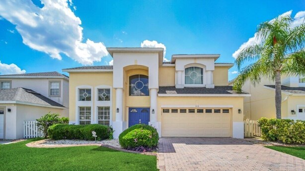 A two-story house with a garage, a well-maintained lawn, and a paved driveway.