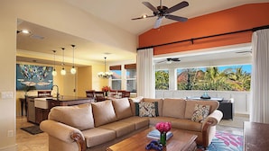 A spacious living room with a large sectional sofa, a wooden coffee table, and a view of the outdoors. - Penthouse with Panoramic Ocean Views From Private Lanais (Koloa)