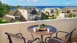 A balcony with a round table, two chairs, and a small potted plant. - Penthouse with Panoramic Ocean Views From Private Lanais (Koloa)