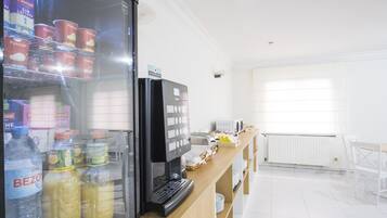 Una kitchenette con un refrigerador lleno de bebidas, un tostador y una cafetera.