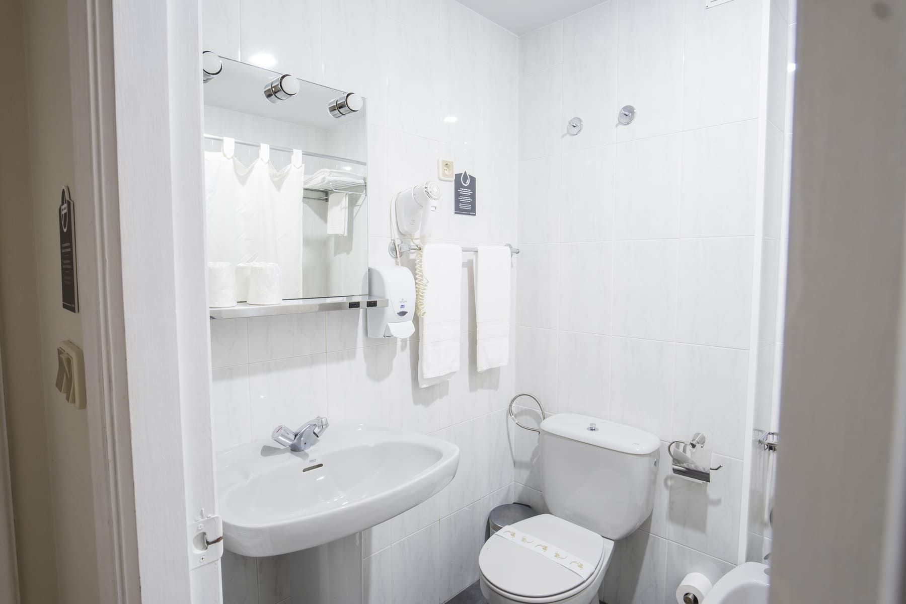 A modern bathroom with a white sink, mirror, and toilet.