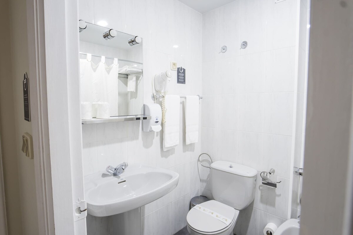 Et moderne badeværelse med hvid vask, spejl og toilet.