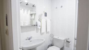 A modern bathroom with a white sink, mirror, and toilet.