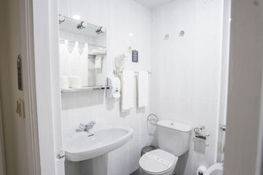Et moderne badeværelse med hvid vask, spejl og toilet.
