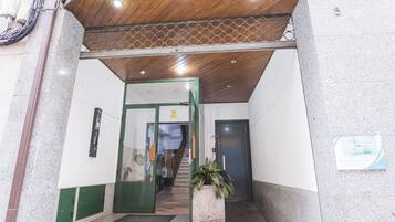 A building entrance with a wooden ceiling, a green door, and a staircase leading inside.