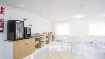 Una cafetería limpia y moderna, con una máquina de café, un tostador y estantes llenos de condimentos y refrigerios.