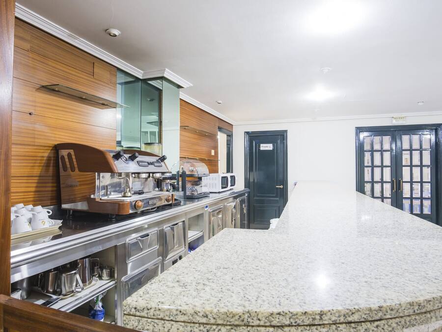 A hotel lobby with a marble reception desk, wooden paneling, a coffee machine, and a private door.