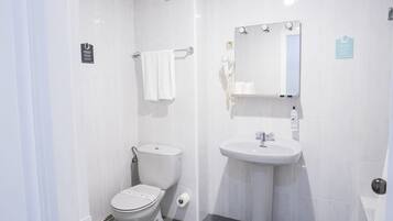 A small, clean bathroom with a toilet, sink, and mirror.