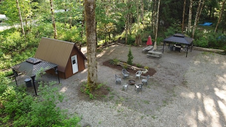 A cabin with a small porch, a covered seating area, and a fire pit.