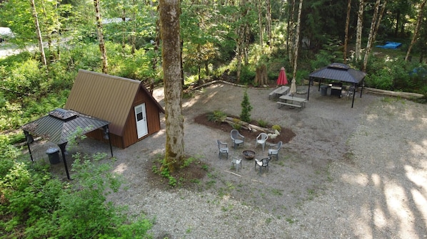 A cabin with a small porch, a covered seating area, and a fire pit.