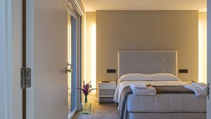 A modern bedroom with a large bed, bedside tables, a nightstand, and a vase with flowers. - Aparthotel Ría de Lires (1 Estrella) (Cee)
