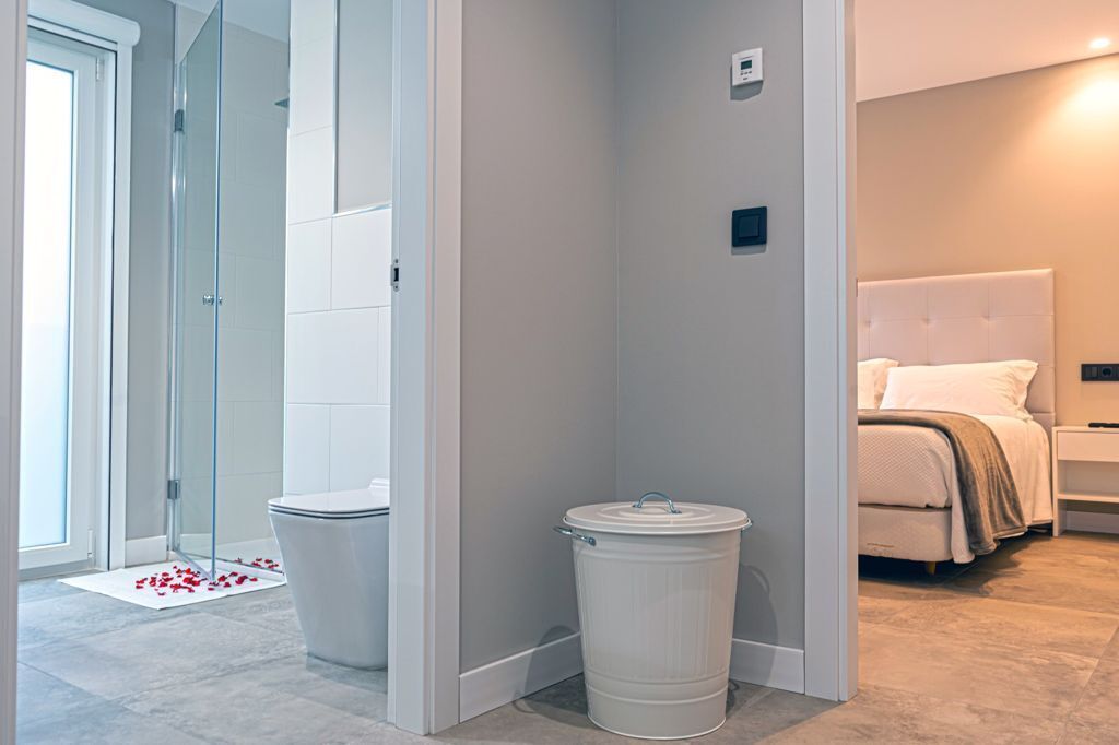 Un baño moderno con cabina de ducha de vidrio, inodoro y cubo de basura.