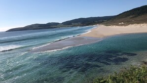 A beach with clear turquoise waters, sandy shore, and hills in the background. - Aparthotel Ría de Lires (1 Estrella) (Cee)