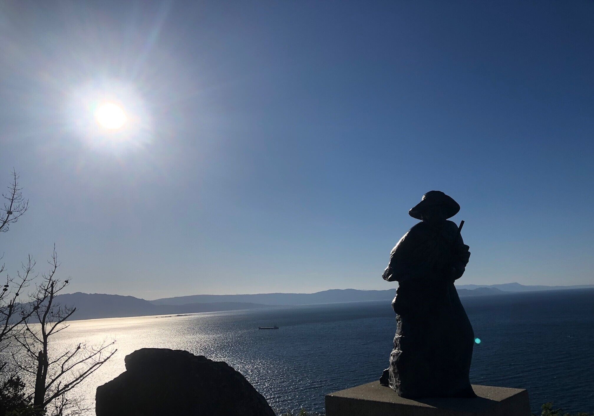 Una estatua que domina un cuerpo de agua bajo un cielo despejado.