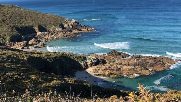A coastal landscape with rocky terrain and clear blue waters.