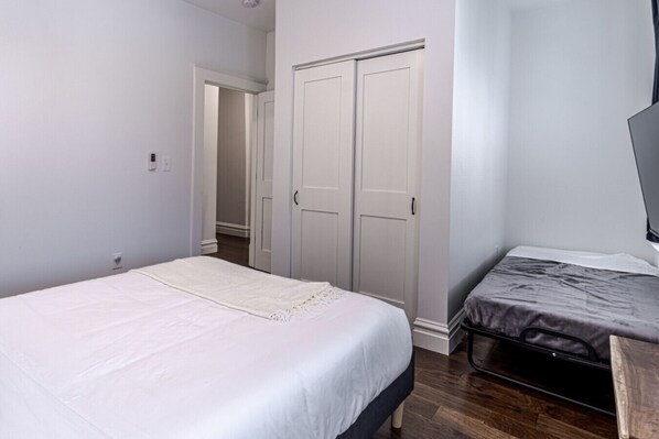 A bedroom with a single bed, a small desk, and a wardrobe.
