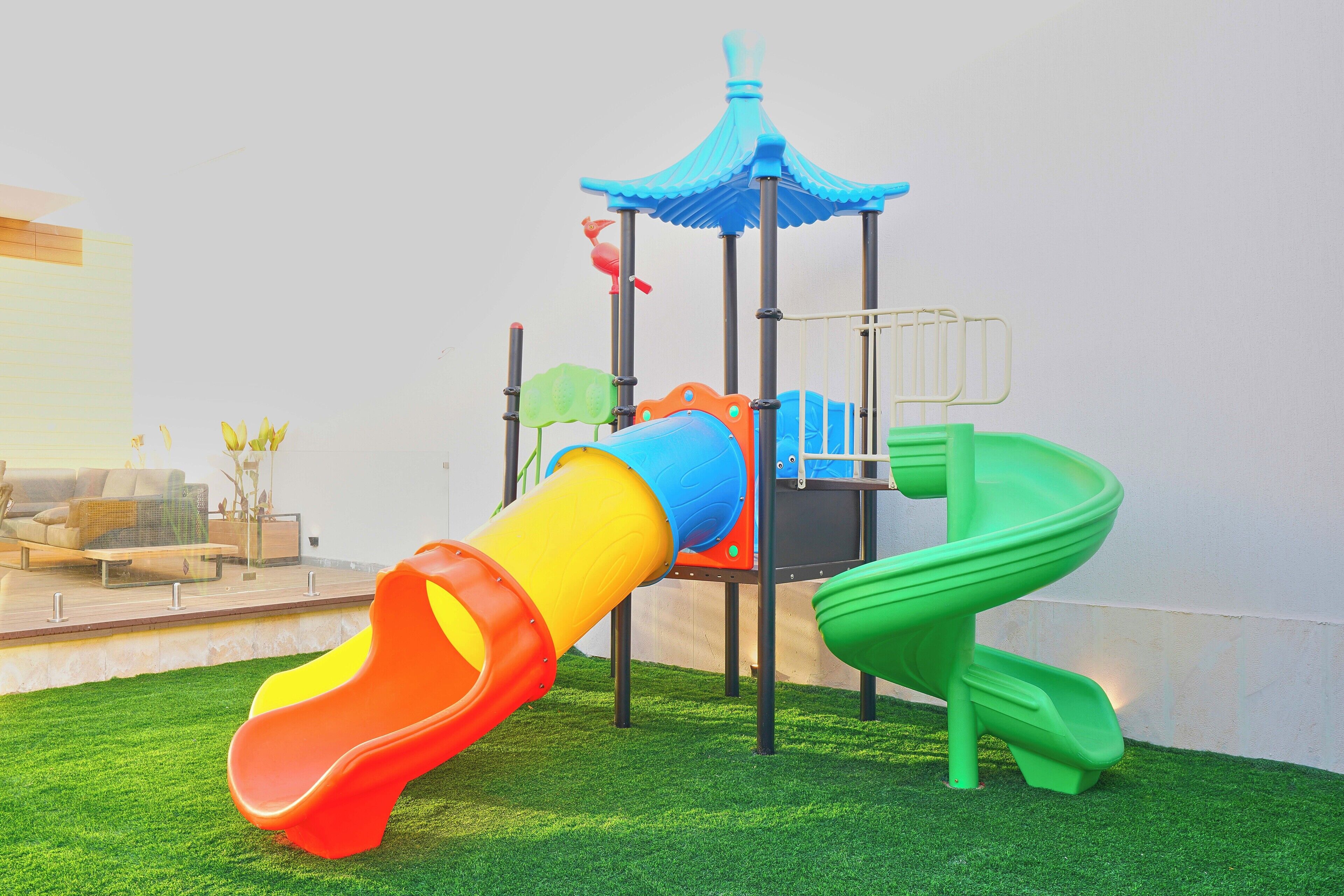 Un parque infantil con un tobogán, una estructura de escalada y un pequeño pabellón.