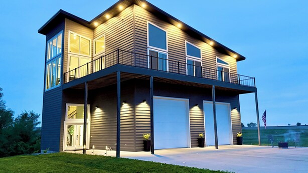 A two-story house with a balcony, large windows, and a garage.