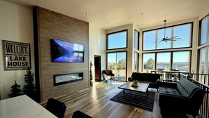 A spacious living area with a large TV, wooden panel wall, and a view of the outdoors.