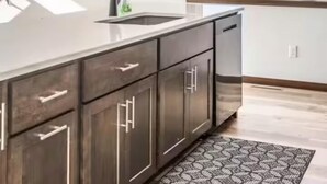 A modern kitchen with a large island, dark wooden cabinets, a window with a view, and pendant lighting.