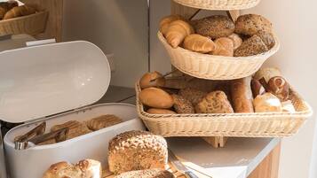 Diverse broden en gebak, waaronder croissants, baguettes en sneetjes brood, gepresenteerd op een toonbank.
