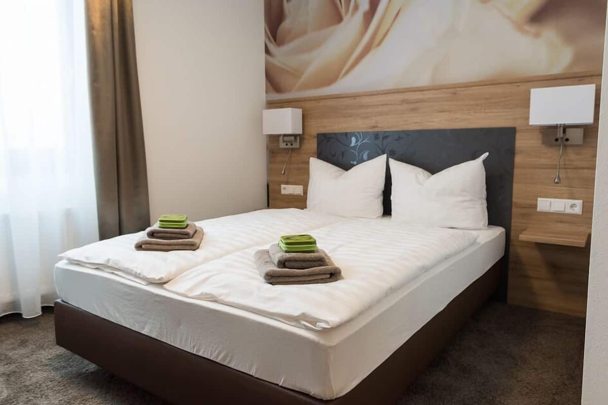 A hotel room with a large bed, two bedside lamps, and a headboard with a floral pattern.