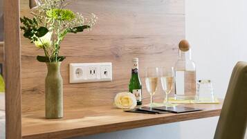 Ein Holztisch mit einer Blumenvase, einer Champagnerflasche, Gläsern und einem Smartphone.