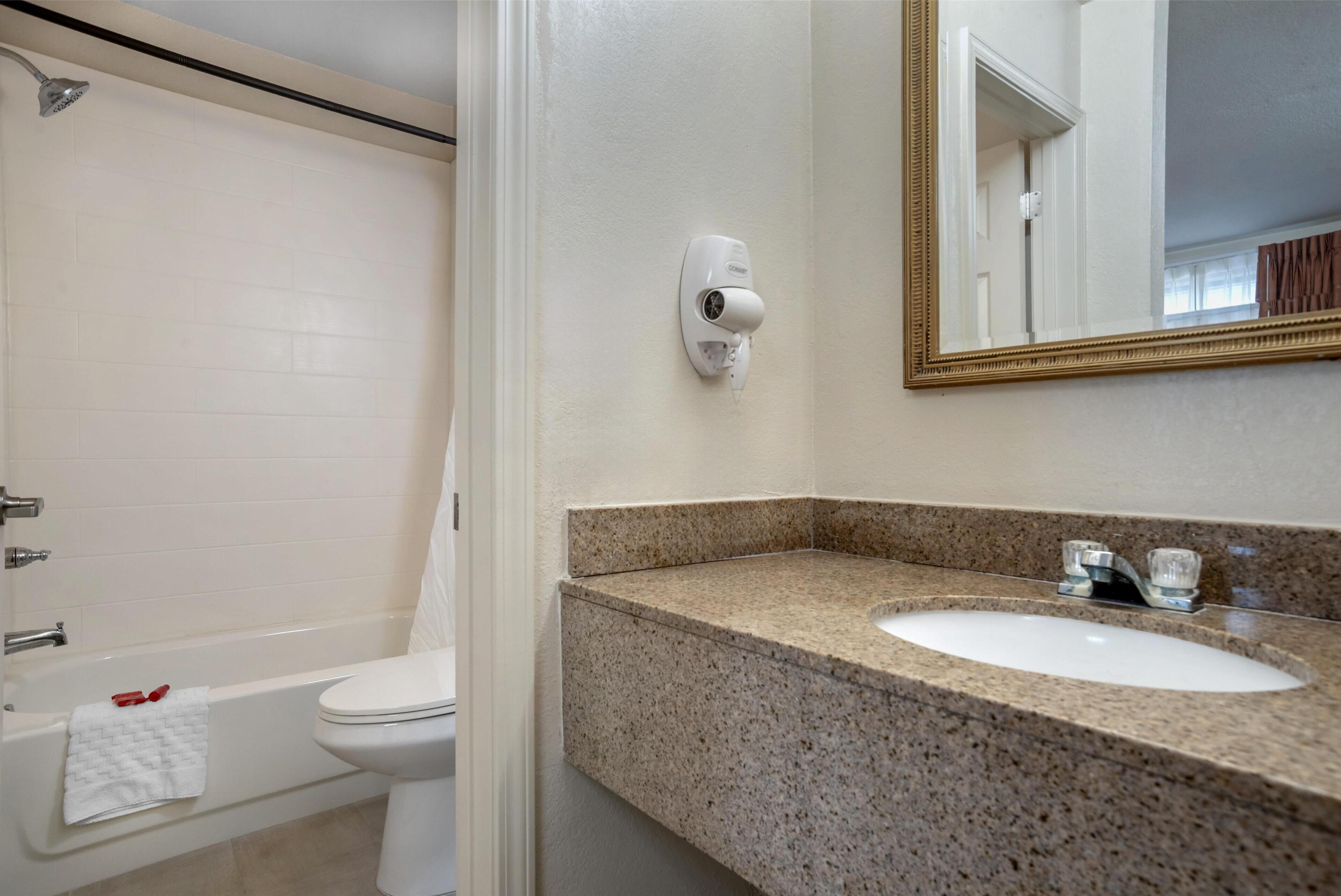 A bathroom with a bathtub, toilet, and a sink with a mirror above it.