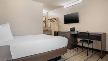 A hotel room with a bed, a desk with a chair, a flat-screen TV, and a coffee maker.