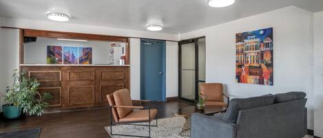 A lobby with a reception desk, a blue door, a gray sofa, and a large painting on the wall.