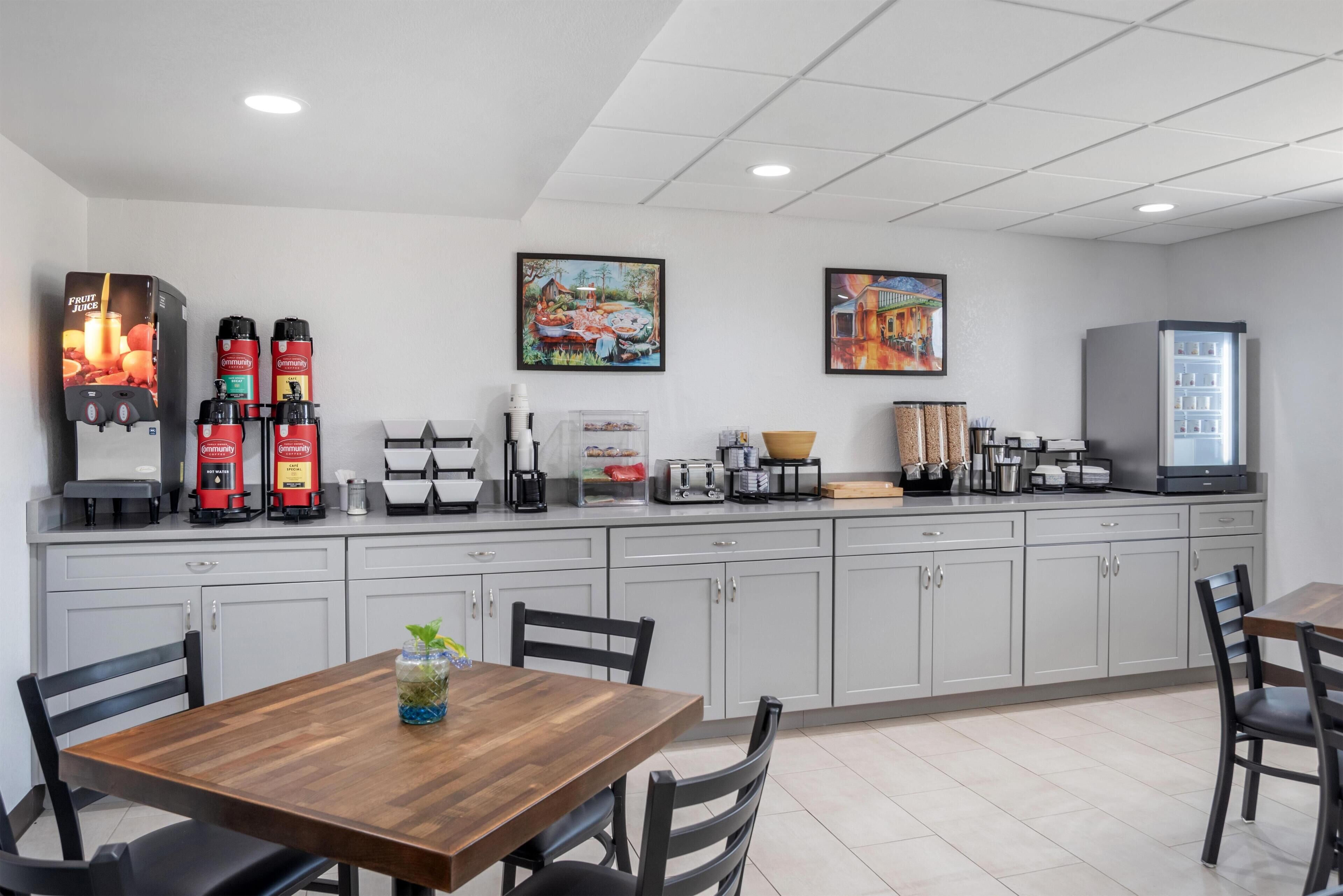A modern kitchen with a coffee station, a refrigerator, and a dining area with chairs and a table.