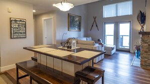 Un vaste espace de vie comprenant une grande table à manger en bois, un ensemble de canapés et une cheminée en pierre.