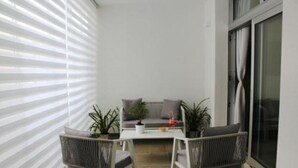A balcony with a sofa, two chairs, a small table, and potted plants. - Central Apartment Olbia-San Simplicio (Oblia)