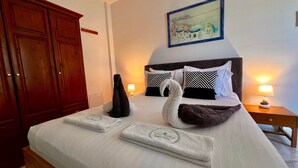 Ein aufgeräumtes Bett mit Handtüchern, einem Kopfteil und zwei Nachttischlampen.