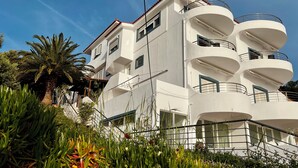 Un immeuble blanc à plusieurs étages, doté de balcons et d  ’un escalier menant à l’entrée.