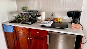 Een keuken met een koffiezetapparaat, een broodrooster, een waterkoker en een koffiemolen op het aanrecht.