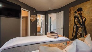Un dormitorio con una cama, un cuadro y una puerta que da a otra habitación.
