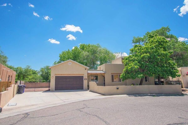 A residential property with a garage, a small attached structure, and a large tree. - Desert Sunset+Private Hot Tub+Pet Friendly! (Albuquerque)