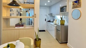 Una cocina moderna con armarios blancos, un refrigerador de acero inoxidable y un comedor con una mesa redonda y sillas.