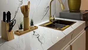 Cocina moderna con encimera de mármol, grifo dorado y diseño minimalista.