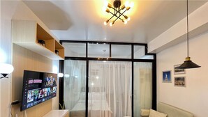 Una sala de estar moderna con un televisor de pantalla plana, un sofá, una mesa de centro y una lámpara de techo.