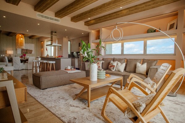 A spacious living area with a wooden coffee table, a sofa, and a dining area with a table and chairs.